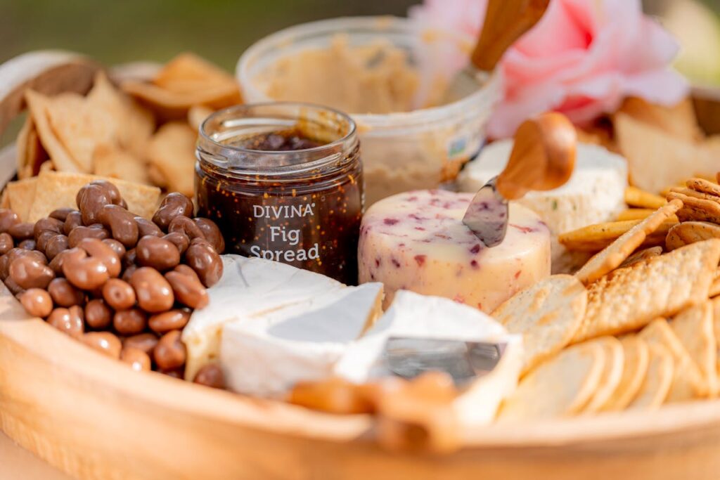 A gourmet platter of cheeses, fig spread, and assorted crackers, perfect for a picnic.
